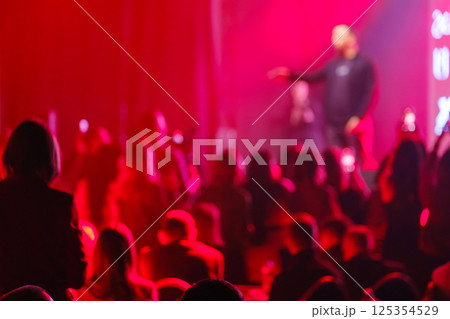 Blurred audience enjoying vibrant red light at live event performance 125354529
