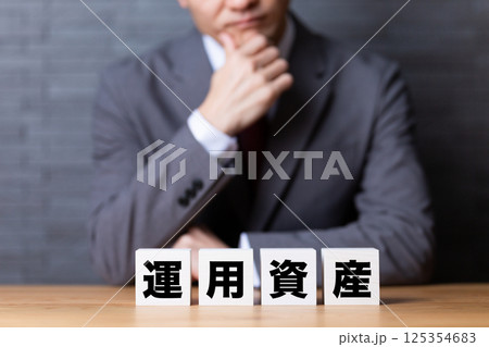 運用資産のブロックとスーツを着て悩むミドル男性ビジネスマン 125354683