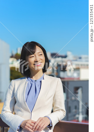 青空の下白いスーツ姿のミドルキャリアウーマン 125355431