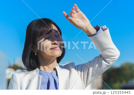 青空の下白いスーツ姿のミドルキャリアウーマン 青空の下白いスーツ姿のミドルキャリアウーマン 125355445