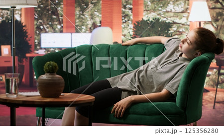 Therapy session with a teenage girl laying on couch discussing trauma and hormonal shifts. Psychotherapist supporting her emotional development, guiding through depression and anxiety. Camera A. Therapy session with a teenage girl laying on couch discussing trauma and hormonal shifts. Psychotherapist supporting her emotional development, guiding through depression and anxiety. Camera A. 125356280