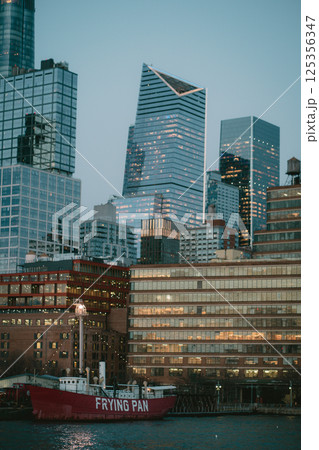 A bright red boat is beautifully docked in front of a stunning city skyline 125356347