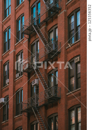 There is a brick building that features a fire escape on its side There is a brick building that features a fire escape on its side 125356352