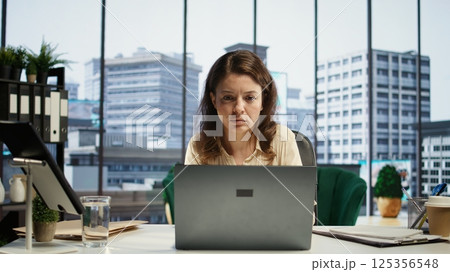 Successful businesswoman analyzes data and market trends on laptop, maximizing income, optimizing expenses and ensuring the company budget. Success story in a global business landscape. Camera B. Successful businesswoman analyzes data and market trends on laptop, maximizing income, optimizing expenses and ensuring the company budget. Success story in a global business landscape. Camera B. 125356548