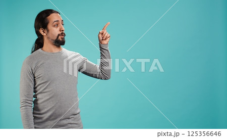 Salesman pointing around with finger, doing recommendation, talking with audience. Man showing copy text space, doing advertisement, isolated over studio background, camera B Salesman pointing around with finger, doing recommendation, talking with audience. Man showing copy text space, doing advertisement, isolated over studio background, camera B 125356646
