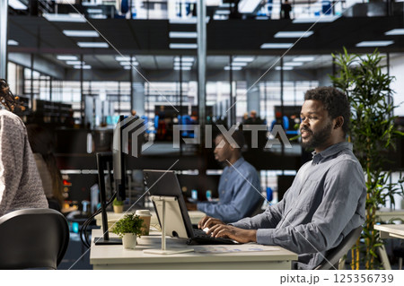 Professional business analyst engages in project management at his desk, working on multinational company growth. Employee focusing on strategy planning to drive corporate success. Professional business analyst engages in project management at his desk, working on multinational company growth. Employee focusing on strategy planning to drive corporate success. 125356739