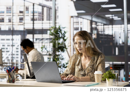 Confident general manager in business attire multitasking at her workplace, juggles email, project deadlines and administrative tasks while maintaining high productivity levels in the office. 125356875