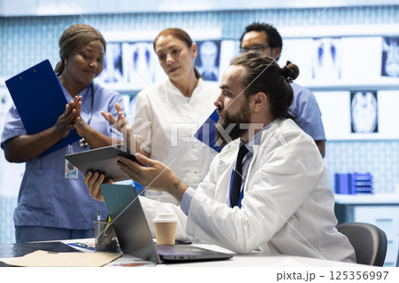 Healthcare experts in a strategic meeting discussing treatment protocols and improvements. Doctors and nurses evaluating diagnostic results in a private clinic to enhance medical services quality. Healthcare experts in a strategic meeting discussing treatment protocols and improvements. Doctors and nurses evaluating diagnostic results in a private clinic to enhance medical services quality. 125356997