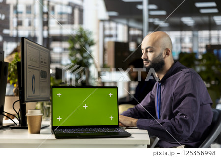 Young corporate analyst handling financial tasks next to chroma key display, preparing a project briefing for the multinational company. Manager reviewing numbers and performance metrics. 125356998