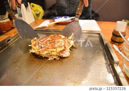 お好み焼きをひっくり返す男性 125357226