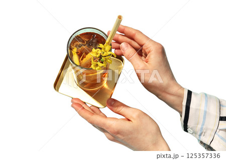 A person holds a glass of iced tea with a fresh garnish on a tray, isolated on white A person holds a glass of iced tea with a fresh garnish on a tray, isolated on white 125357336