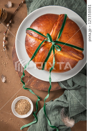 Portuguese traditional Easter cake Folar without eggs on easter table with a green velvet bow and a bowl of fennel seeds. Top view 125358081