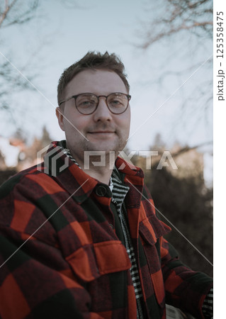Handsome Man Looking at Camera, Close-Up Portrait with Confident Expression outdoors 125358475