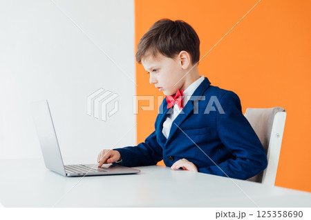 Boy in school uniform working on laptop Boy in school uniform working on laptop 125358690