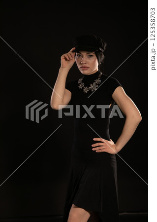 Beautiful brunette woman in black evening dress and cap Beautiful brunette woman in black evening dress and cap 125358703