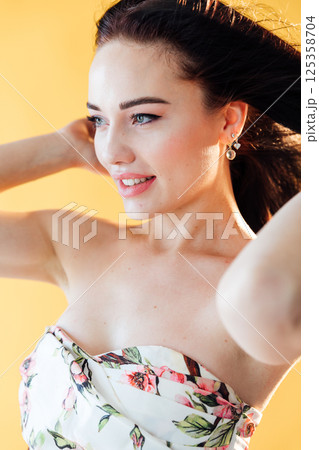 Portrait of a beautiful brunette woman in a dress with flowers Portrait of a beautiful brunette woman in a dress with flowers 125358704