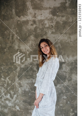 woman in summer white dress smiling on gray background woman in summer white dress smiling on gray background 125358943