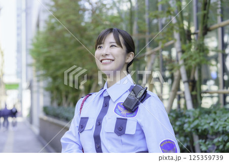 オフィスビルの前に立つ若い女性警備員 撮影協力:学校法人電波学園 東京電子専門学校 オフィスビルの前に立つ若い女性警備員 撮影協力:学校法人電波学園 東京電子専門学校 125359739