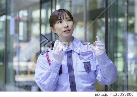 ビルの前でトランシーバーで会話する若い女性警備員 撮影協力:学校法人電波学園 東京電子専門学校 ビルの前でトランシーバーで会話する若い女性警備員 撮影協力:学校法人電波学園 東京電子専門学校 125359806