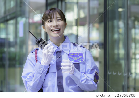 ビルの前でトランシーバーで会話する若い女性警備員 撮影協力:学校法人電波学園 東京電子専門学校 ビルの前でトランシーバーで会話する若い女性警備員 撮影協力:学校法人電波学園 東京電子専門学校 125359809