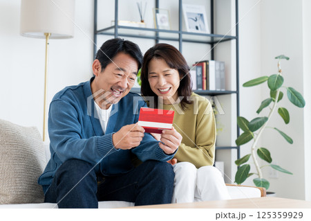 リビングで通帳を見るミドルの夫婦 125359929