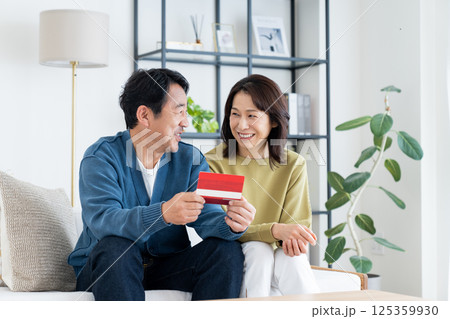 リビングで通帳を見るミドルの夫婦 125359930