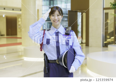 オフィスビルのロビーに立つ敬礼する若い女性警備員　撮影協力：学校法人電波学園 東京電子専門学校 125359974