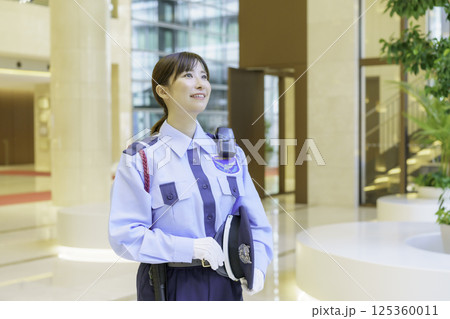 オフィスビルのロビーに立つ若い女性警備員　撮影協力：学校法人電波学園 東京電子専門学校 125360011