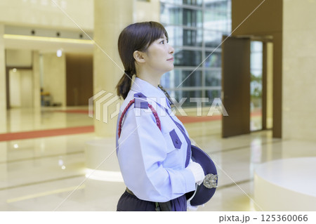 オフィスビルのロビーに立つ若い女性警備員の横顔　撮影協力：学校法人電波学園 東京電子専門学校 125360066