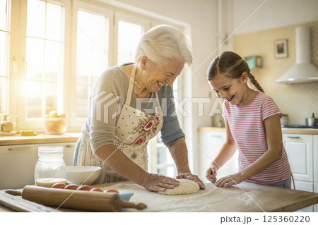 Grandma in the kitchen kneading dough with her granddaughter 125360220