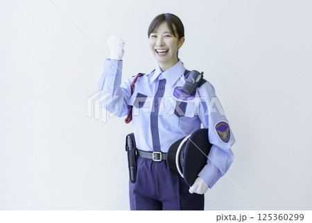 白背景のガッツポーズをする若い女性警備員のポートレート　撮影協力：学校法人電波学園 東京電子専門学校 125360299