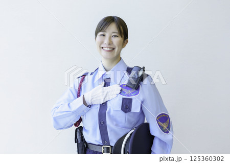 白背景の胸に手を当てる若い女性警備員のポートレート　撮影協力：学校法人電波学園 東京電子専門学校 125360302