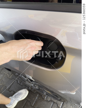 Close up of driver's hand opening gas tank of car at gas station. Preparation for refueling. 125360359