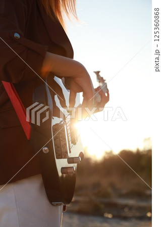 Girl Plays Bass Music Instrument On The Beach At Sunset Near Ocean Girl Plays Bass Music Instrument On The Beach At Sunset Near Ocean 125360868