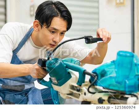 電動ノコギリを使って木材を切る男性　DIY 125360974