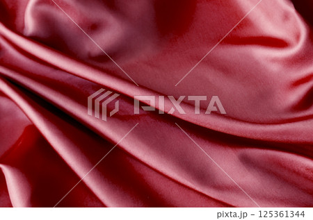 Vibrant dark red fabric draped in soft, smooth waves with a glossy finish. Suitable for design and wallpaper background. Vibrant dark red fabric draped in soft, smooth waves with a glossy finish. Suitable for design and wallpaper background. 125361344
