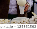 a woman behind a counter with national Kazakh dishes pours a glass of shubat kefir made from camel milk 125361592