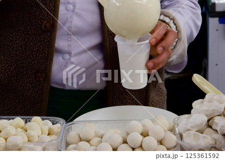 a woman behind a counter with national Kazakh dishes pours a glass of shubat kefir made from camel milk a woman behind a counter with national Kazakh dishes pours a glass of shubat kefir made from camel milk 125361592