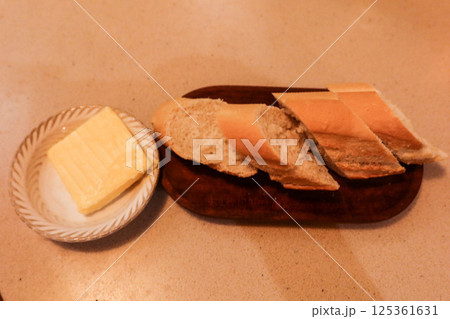 close up of a baguette bread cut into piece, with a small block of butter on the side 125361631