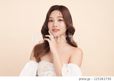 A beautiful young Asian woman with clean, fresh skin against a beige background. Skincare, facial treatment, cosmetology, beauty, and spa. An elegant portrait of an Asian woman. A beautiful young Asian woman with clean, fresh skin against a beige background. Skincare, facial treatment, cosmetology, beauty, and spa. An elegant portrait of an Asian woman. 125361730