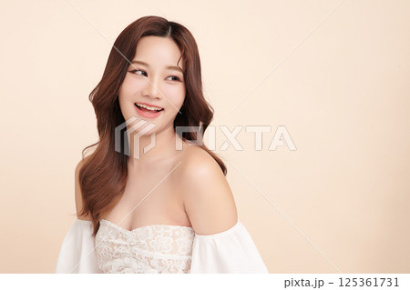 A beautiful young Asian woman with clean, fresh skin against a beige background. Skincare, facial treatment, cosmetology, beauty, and spa. An elegant portrait of an Asian woman. A beautiful young Asian woman with clean, fresh skin against a beige background. Skincare, facial treatment, cosmetology, beauty, and spa. An elegant portrait of an Asian woman. 125361731
