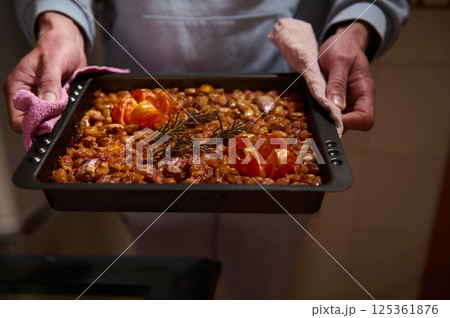 A close-up of a mouthwatering tray of baked beans just out of the oven, garnished with fresh rosemary and baked tomatoes. The vibrant tones highlight the dish's irresistible aroma. A close-up of a mouthwatering tray of baked beans just out of the oven, garnished with fresh rosemary and baked tomatoes. The vibrant tones highlight the dish's irresistible aroma. 125361876