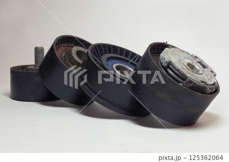 tensioner, idlers, pulleys of car actuators of engine and alternator. dismantled rollers of car drive mechanisms, stacked in line 125362064