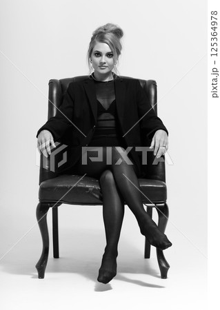Black and white portrait of beautiful woman with tight black clothes sitting on vintage armchair Black and white portrait of beautiful woman with tight black clothes sitting on vintage armchair 125364978