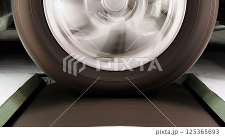 Close-up of spinning vehicle wheel with motion blur of rim and tire during high-speed testing. Measure energy and dynamics performance against rotational friction roller in lab Close-up of spinning vehicle wheel with motion blur of rim and tire during high-speed testing. Measure energy and dynamics performance against rotational friction roller in lab 125365693