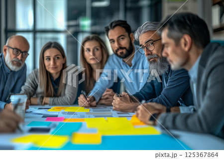 A group of people are sitting around a table with a lot of papers A group of people are sitting around a table with a lot of papers 125367864