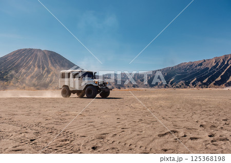 Off road vehicle parked by the Volcanic Mount Bromo on desert wilderness at Indonesia 125368198