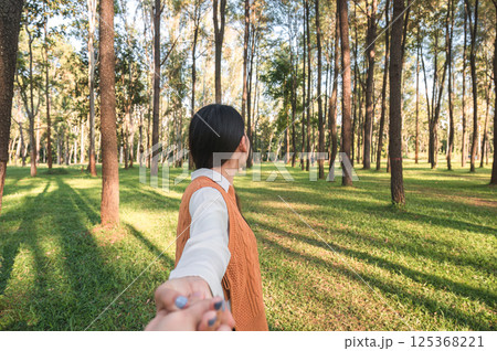Woman holding hands in pine forest during the evening 125368221