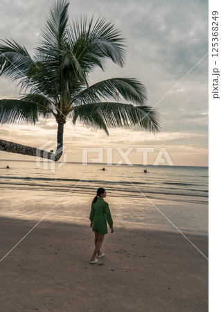 Asian woman walk along the beach under palm tree in the evening during summer vacation Asian woman walk along the beach under palm tree in the evening during summer vacation 125368249