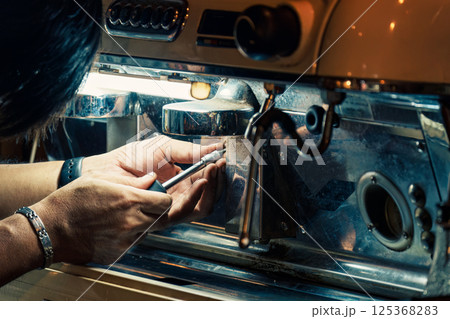 Technician using screwdriver removing nut from coffee maker in coffee shop 125368283